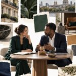 AI-generated collage of a woman and a man in discussion across a round table with notebooks and balanced wooden shapes.